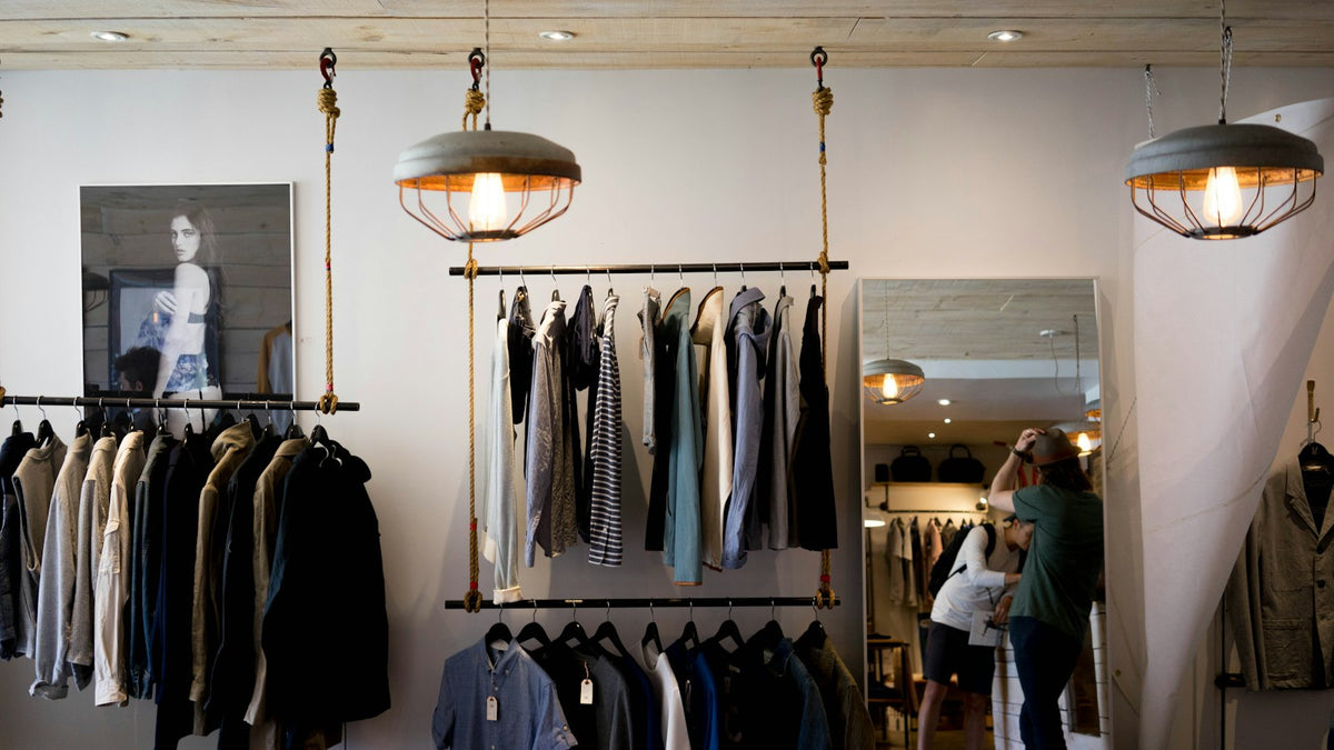 Garment rail in a moody boutique interior — the Galliano x Zara collection brings couture technique to the high-street rack