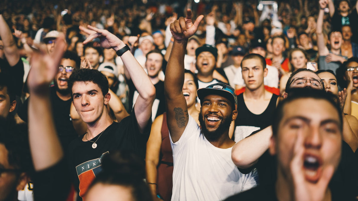 Concert crowd with raised hands under moody stage lighting — what to wear to a concert