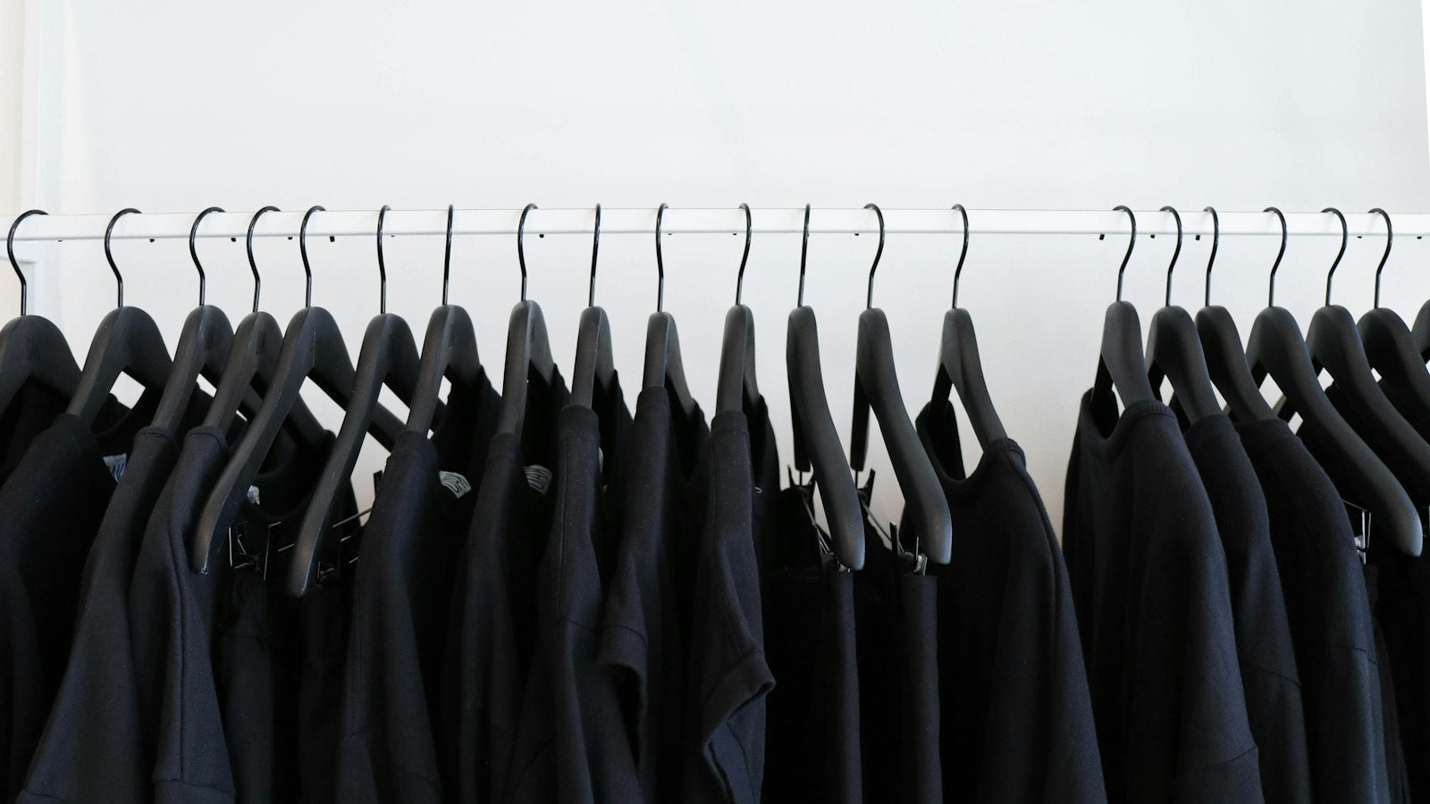 Deadstock meaning: rail of garments hanging in a dark archive, pieces that will never restock
