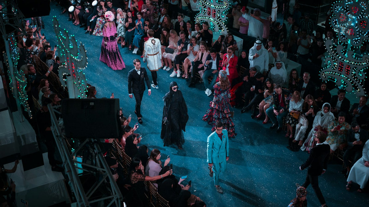 Front row outfits at a fashion week runway show — models on stage under editorial lighting