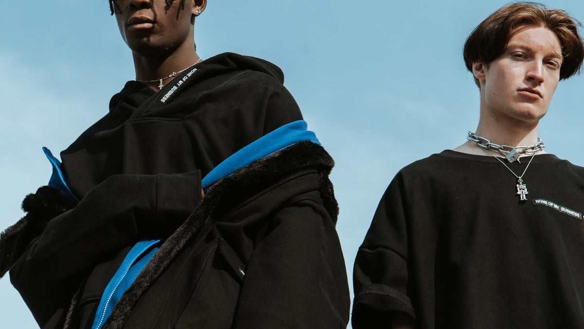 Two men in coordinated streetwear color combinations standing against an urban backdrop