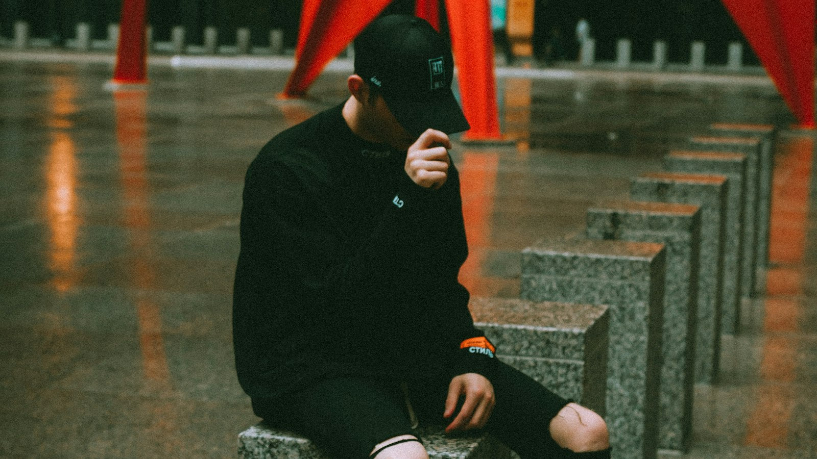 Supreme x Nike Fall 2026 mood: black jacket and knit cap layered for cold weather in moody city light