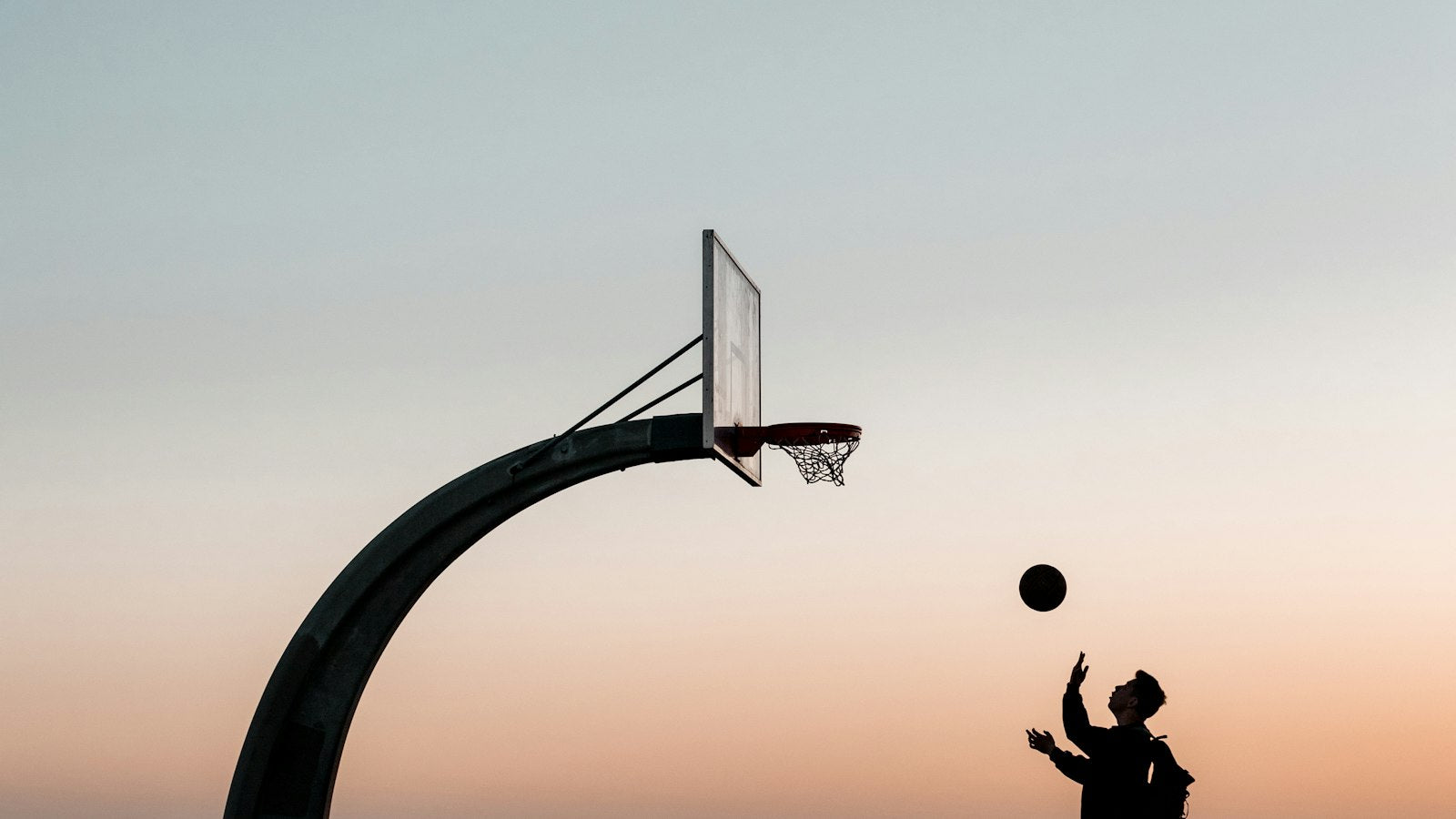 LeBron James 76ers era: lone player in black on an outdoor basketball court at sunset