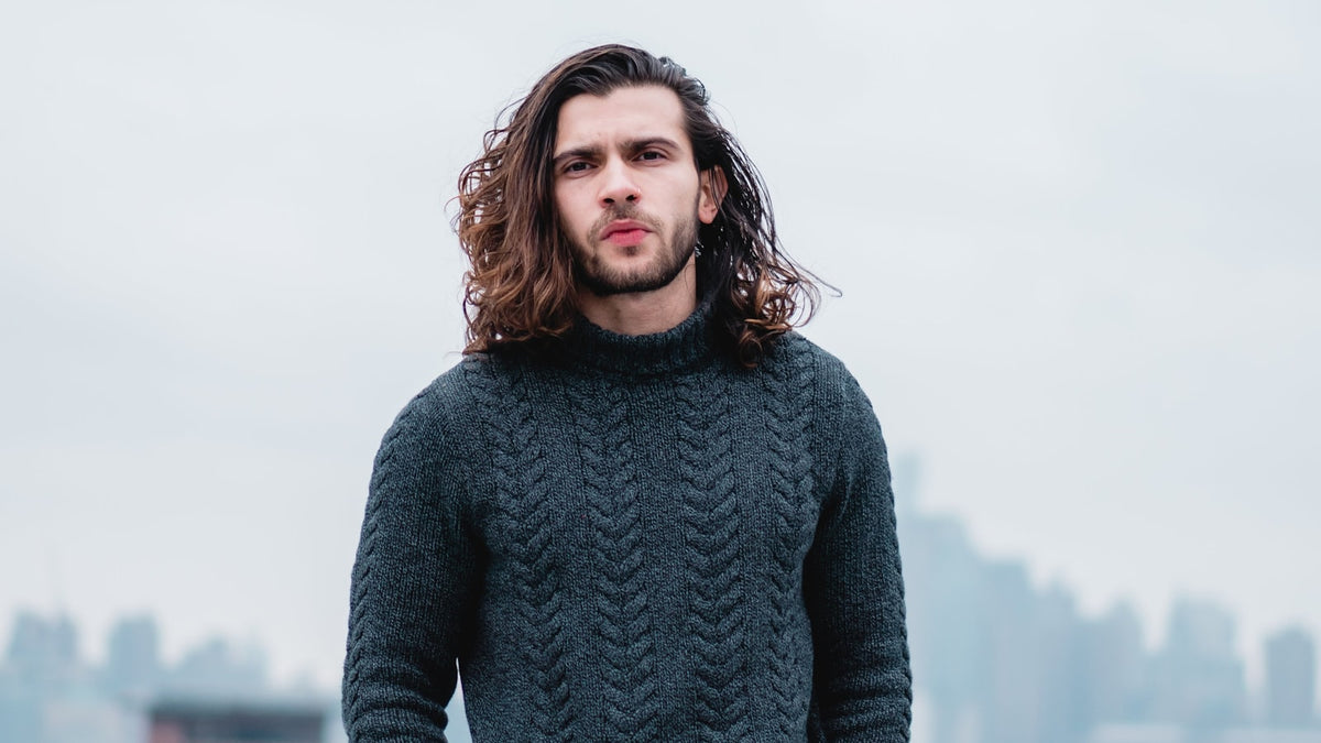 Man in a grey knit sweater outdoors in muted tones — how to style knitwear for streetwear