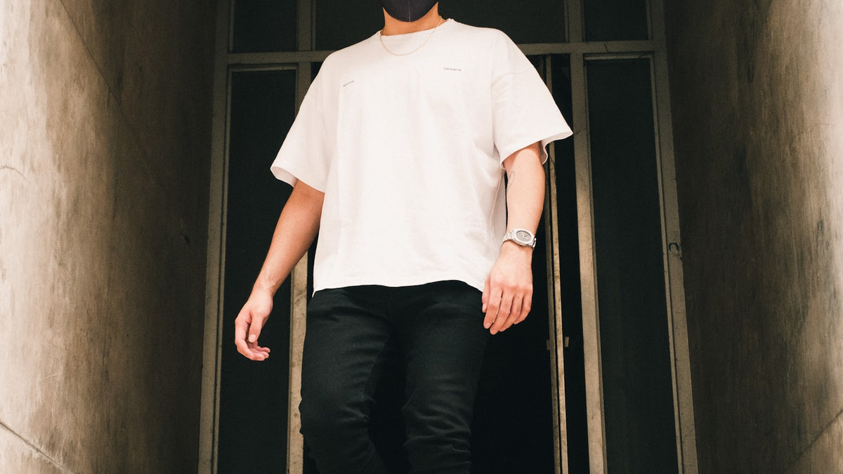 How to style sweatpants: minimalist streetwear fit with white crewneck and black pants in an urban hallway