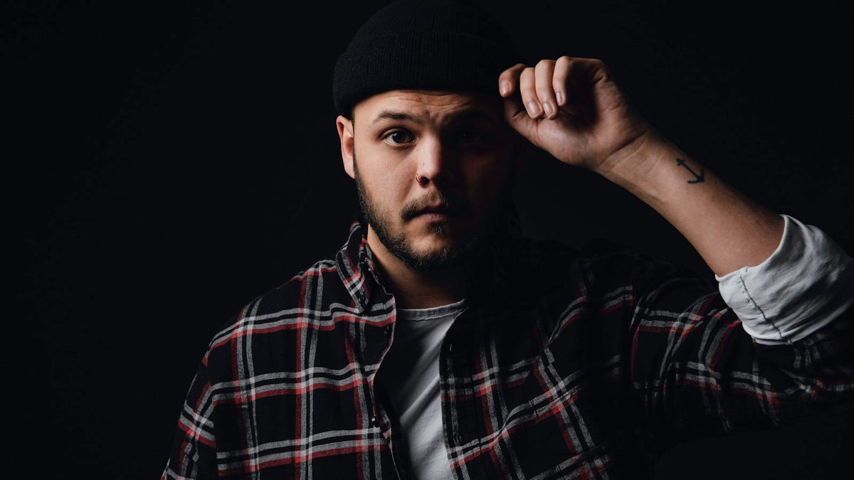 Man wearing a plaid flannel overshirt and cap on a city street — how to style an overshirt for fall
