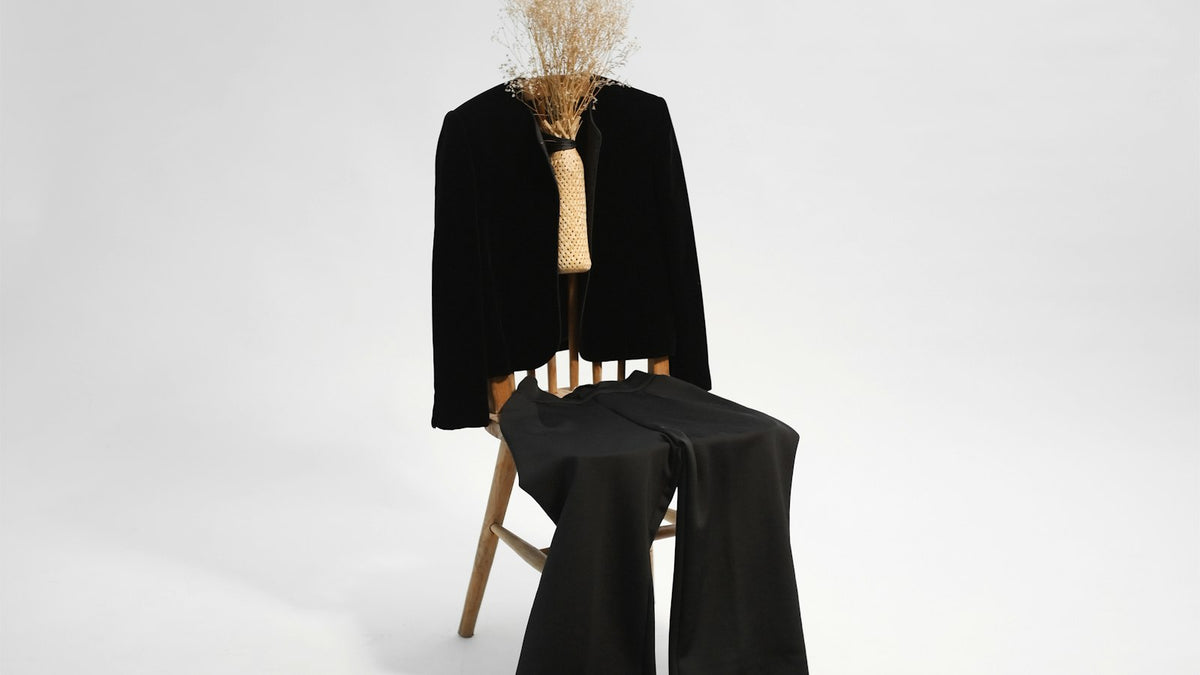 Quiet luxury in practice: a minimal black coat in a bare studio, all fabric and no logo