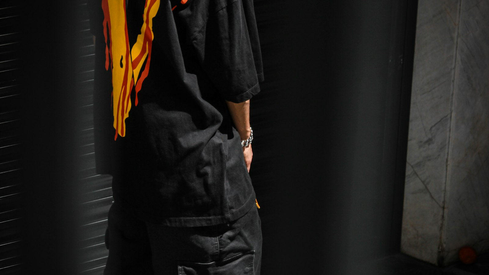 How to layer clothes for fall: man in a hat and black jacket in a moody urban streetwear setting