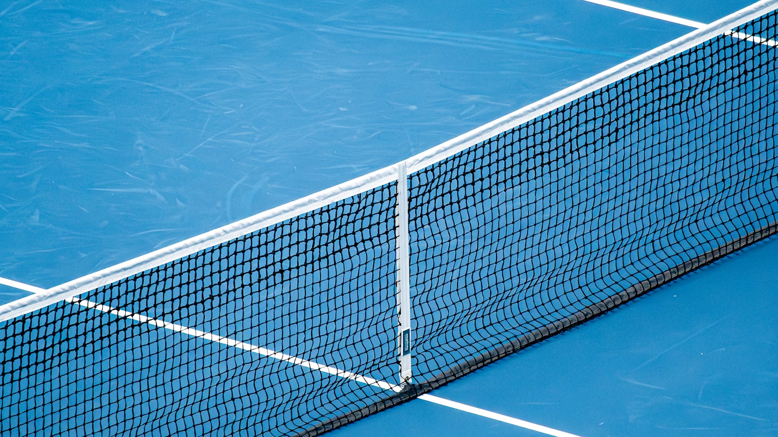 Black tennis net across a blue hard court with white lines — Travis Scott x Nike Cactus Court and the US Open
