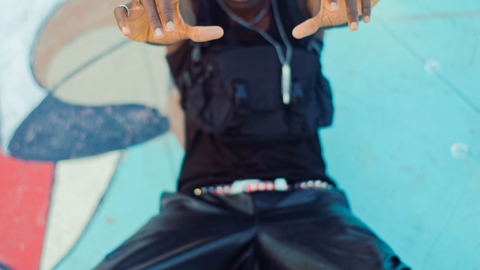 Skater in an all black outfit sitting on a skateboard in an urban skate park