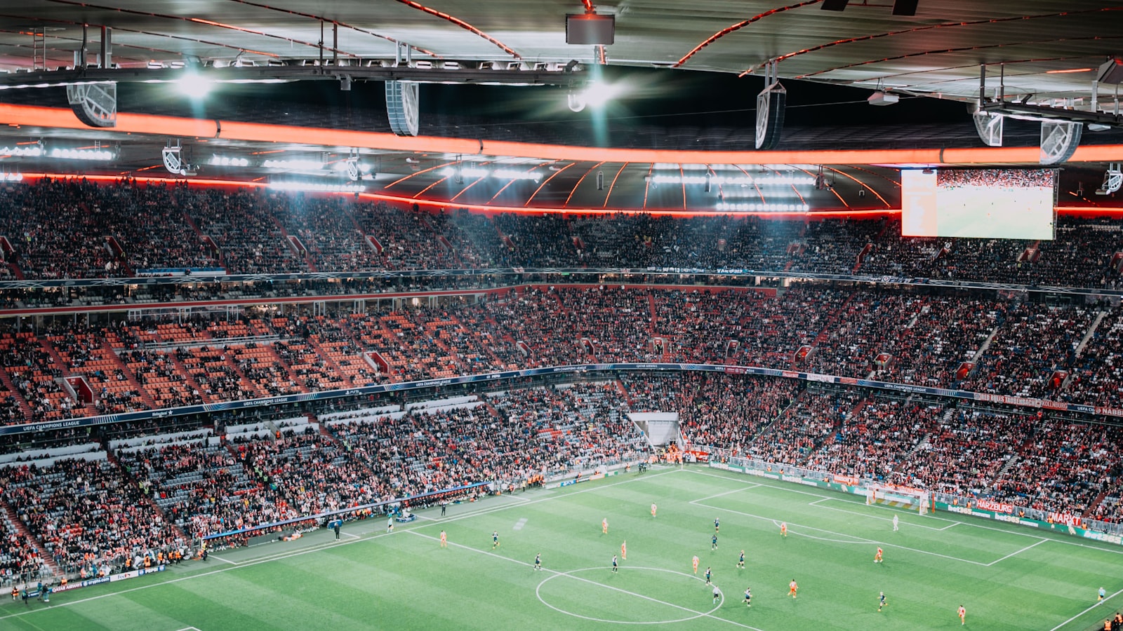 What to wear to a football match — packed football stadium under floodlights at night