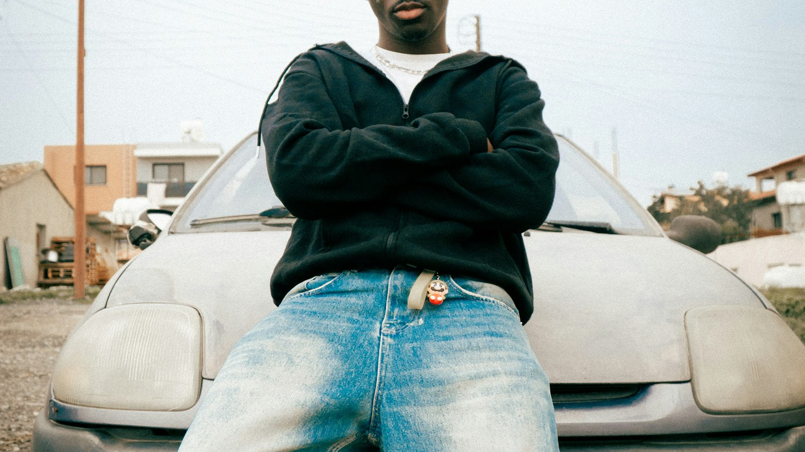 How to style baggy jeans: man in baggy jeans leaning on a car hood, urban street style