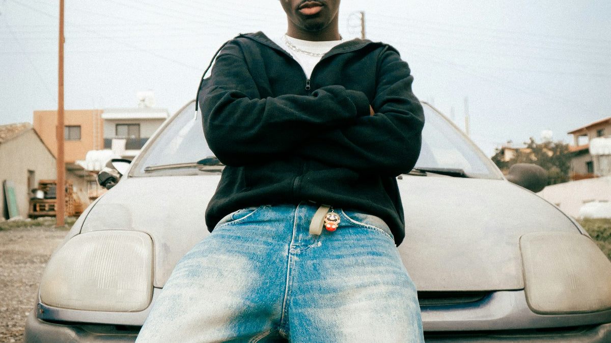 How to style baggy jeans: man in baggy jeans leaning on a car hood, urban street style