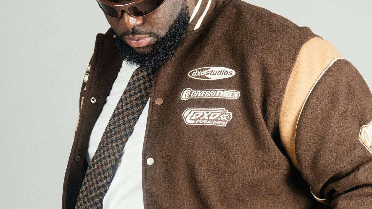 How to style a varsity jacket — man in a brown varsity jacket and sunglasses, editorial street style
