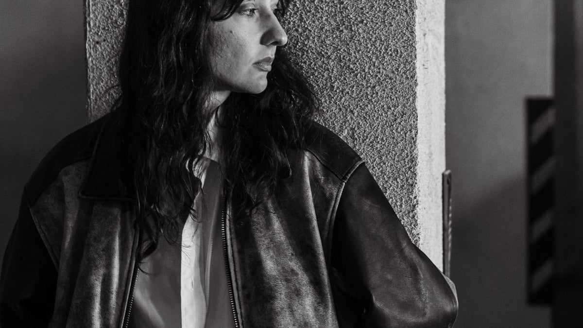 How to style a bomber jacket — editorial street style shot of a bomber jacket worn against city architecture